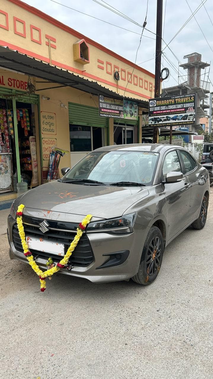A photo of a Maruti Dzire 2026 - Gray sedan with garland.